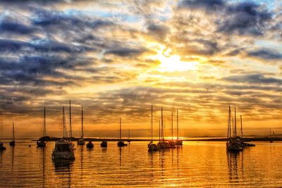 Sailboats in sea at sunset