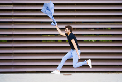 Side view of businessman jumping against wall