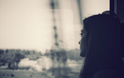 Depressed woman looking through window while traveling in vehicle