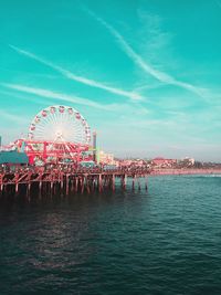 View of ferris wheel by sea against sky