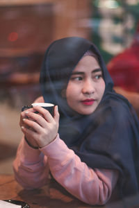 Portrait of young woman sitting on table