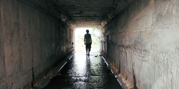 Rear view of man walking in tunnel