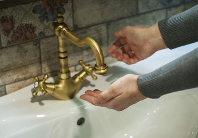 Cropped hands of woman washing hands in sink