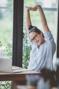 Businesswoman with arms raised looking at laptop on table in cafe