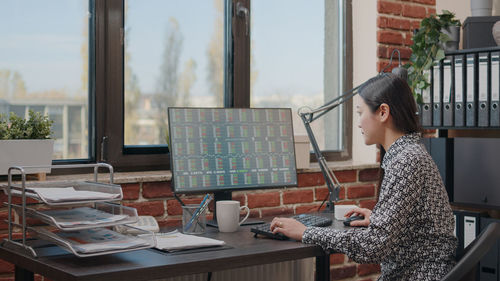 Young woman using laptop while sitting on table