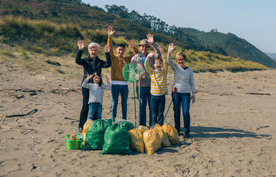 Group of volunteers posing with full garbage bags after cleaning the beach