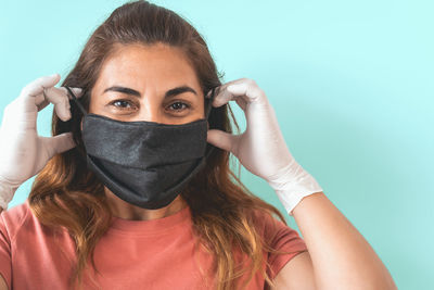 Portrait of young woman covering face against blue background