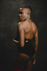Man looking away while standing against black background