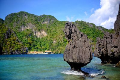 Scenic view of rocks by sea against sky