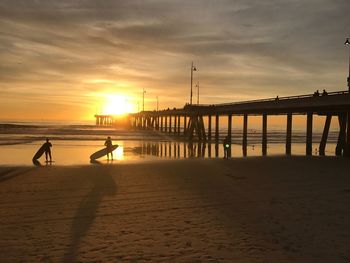 Silhouette people on beach against sky during sunset