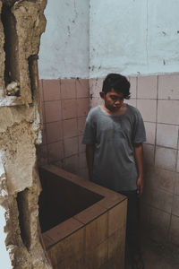 Portrait of boy standing against wall