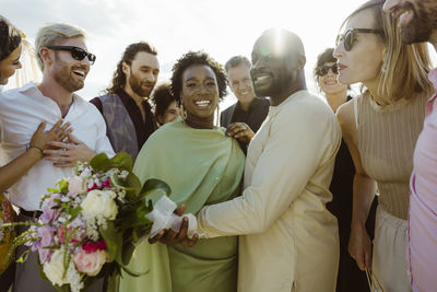 Portrait of happy newly married couple amidst happy guests at wedding ceremony
