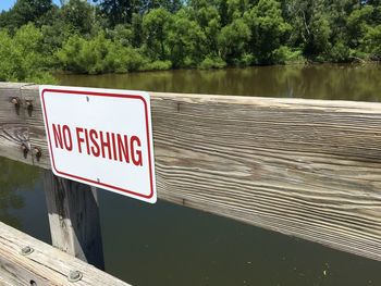 Information sign by lake against trees