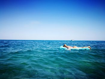 Bikini woman sleeping on pool raft in sea