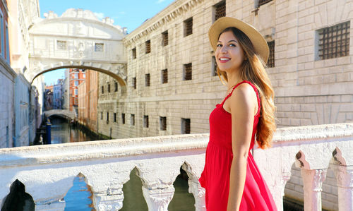 Smiling young woman wearing hat standing by canal