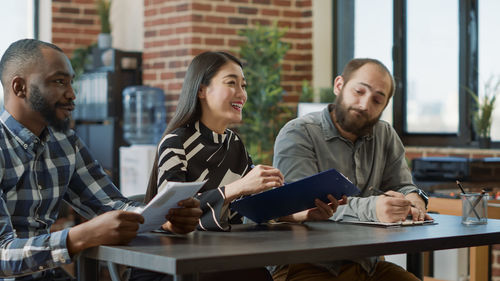 Man and woman sitting on desk at office