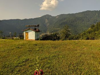 Built structure on field by mountain against sky