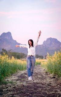 Rear view of woman standing on field against sky during sunset