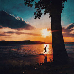 Silhouette person on beach against sky during sunset