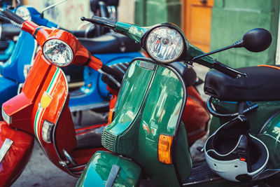 Shiny vintage motorcycles of various bright colors parked in row on city street