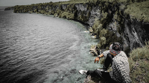 People sitting on rock by sea