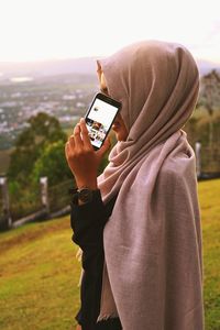 Close-up of woman using mobile phone against sky