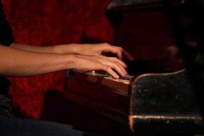 Midsection of man playing piano in darkroom