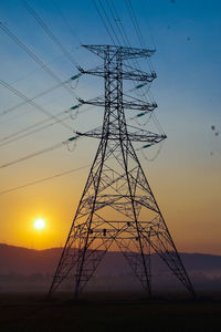 Low angle view of silhouette electricity pylon against sky during sunset