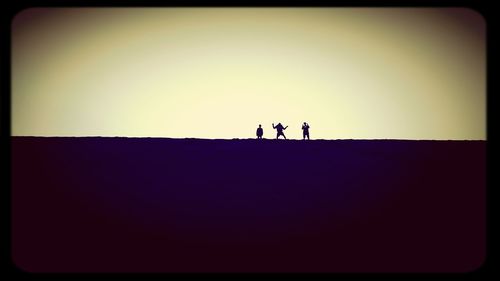 Silhouette people standing against clear sky during sunset