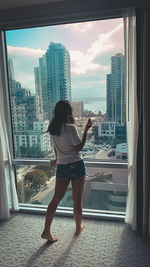 Rear view of woman standing by buildings against sky