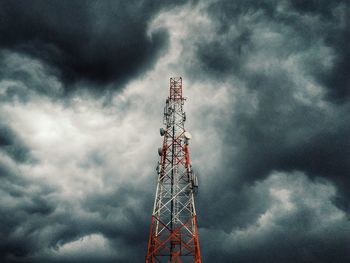 Low angle view of communications tower against cloudy sky