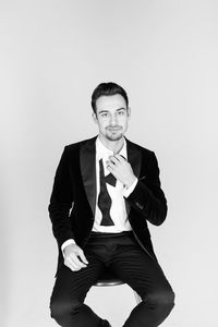 Portrait of young man in suit standing against gray background