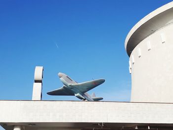 Low angle view of airplane flying against clear blue sky