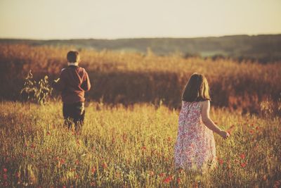 Rear view of children standing on field