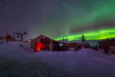 Houses on snow covered field against sky at night