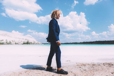 Full length of young woman standing on land against sky