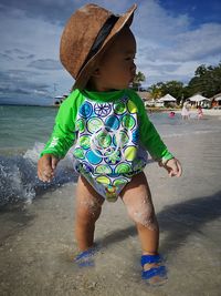 Full length of boy wearing hat in sea