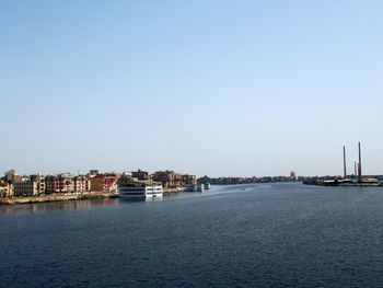 Buildings by sea against clear sky