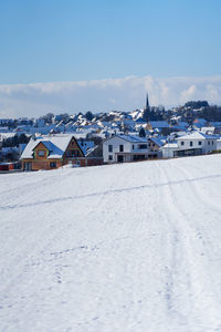 Snow covered houses by buildings against sky