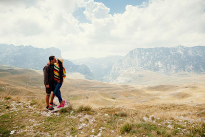 Full length of couple kissing on mountain against sky