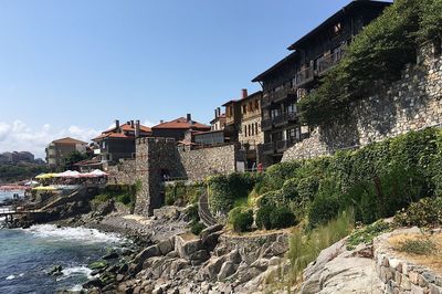 Buildings by river against sky