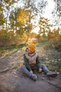 Boy sitting on field during autumn