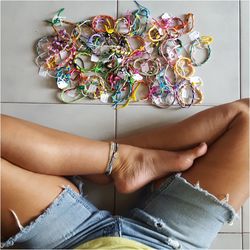 Low section of woman sitting with wristbands sitting on tiled floor