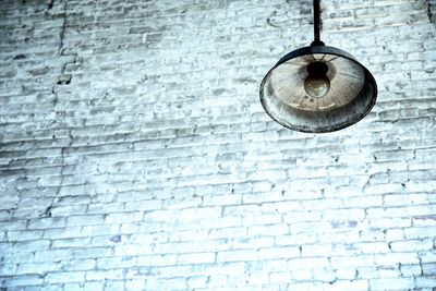 Low angle view of pendant light hanging against white wall