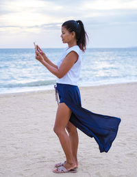 Side view of young woman exercising at beach