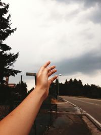 Close-up of person hand on road against sky