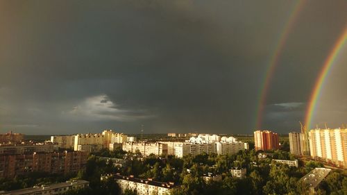 Rainbow over city buildings against sky