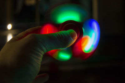 Close-up of hand holding illuminated fidget spinner