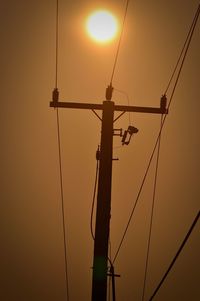 Low angle view of telephone pole against sky during sunset