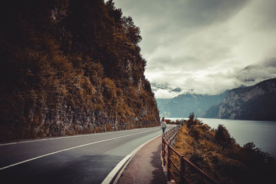 Road by mountain against cloudy sky